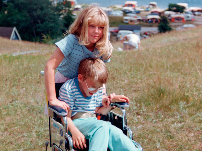Veronica som barn står bakom sin bror Thommy som sitter i rullstol