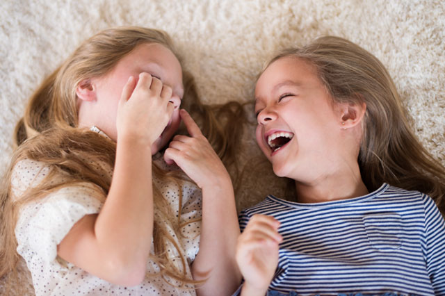 Flickor som ligger ner och skrattar på en matta